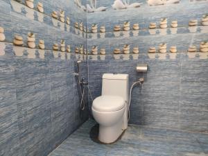 een badkamer met een toilet in een kamer met een muur van huis en huis en huis en bij Corbett Rejoice Home Stay in Jhirna