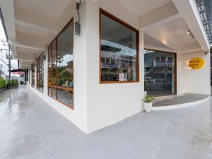 ein weißes Gebäude mit großen Fenstern auf einer Straße in der Unterkunft Moonlight Cafe and Hotel in Tha Sala