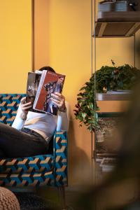 uma mulher sentada numa cadeira a ler um livro em Hotel Jolly Roger em Pietra Ligure