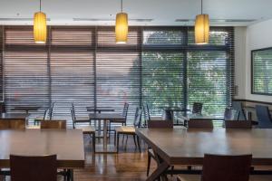 una sala da pranzo con tavoli, sedie e ampie finestre di Hotel Vista Ebina a Ebina