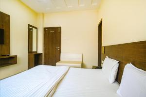 a bedroom with a large white bed and a chair at FabHotel Satyug Jaisinghpura in Ujjain
