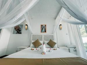 a white bedroom with a bed with white curtains at Milamax Beach Vllla in Diani Beach +42 photos