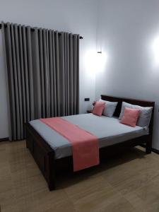 a bedroom with a large bed with pink pillows at Airport Dulux Green Villa in Minuwangoda