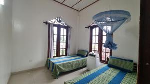 a room with two beds and two windows at Family Tides Guest in Kochchikade