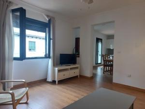 a living room with a tv on a table and a window at Rest . . . Heliópolis in Seville