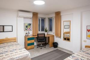 sypialnia z 2 łóżkami, biurkiem i krzesłem w obiekcie Best Value Guest Suite w mieście Rechowot