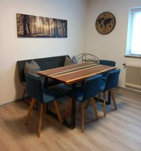 een eettafel met vier stoelen en een klok aan de muur bij Apartment Steirawohnzimmer in Haus im Ennstal