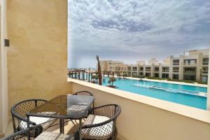 einen Balkon mit einem Tisch, Stühlen und einem Pool in der Unterkunft Modern & Mellow 1 BDR Mangroovy Free Beach & Pool Access in Hurghada