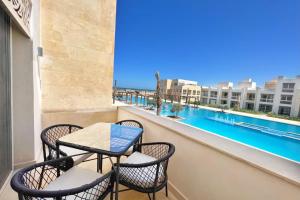 einen Balkon mit einem Tisch und Stühlen sowie einem großen Fenster in der Unterkunft Modern & Mellow 1 BDR Mangroovy Free Beach & Pool Access in Hurghada