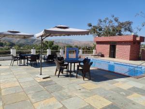 a table and chairs with umbrellas next to a pool at 9 BHK Skyview Villa Udaipur with 2 private pool in Udaipur