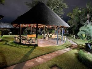 a gazebo with a table and benches in a garden at REED MAT LODGE in Lusaka