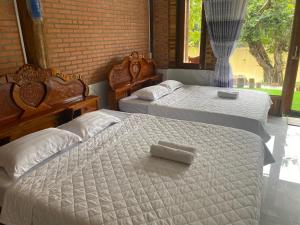 a bedroom with two beds with white sheets and a window at Floor river view in Cat Tien
