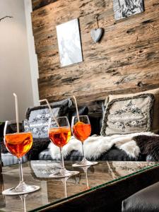 three wine glasses sitting on a table in front of a couch at Panorama Ski Lodge in Zermatt