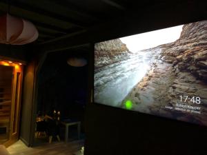 SorbaisにあるPAUSE NATURE SORBAIS Chambre avec SPA, SAUNA, HAMMAM SHOWER, STREAMING et arrivée autonomeの石壁の客室で、薄型テレビが備わります。