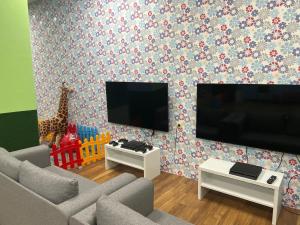 sala de estar con sofá, TV y jirafa en Flora Hotel - Apartments en Borovets