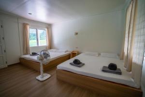 a room with two beds and a fan and a window at Khaosok Eco Raft in Ban Kraison