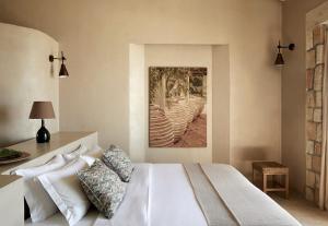 a bedroom with a white bed and a painting on the wall at F Zeen in Lourdata