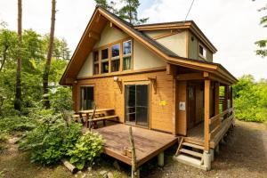 a tiny house in the woods with a deck at Reposer Hakuba Hotel and Offsite Villa in Hakuba