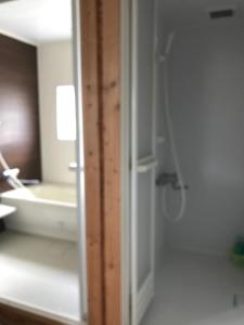 La salle de bains est pourvue d'une douche et d'un miroir. dans l'établissement Rental room Narita "Male Only" - Vacation STAY 58820v, à Kutchan