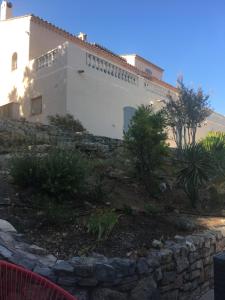 a white building with a stone wall in front of it at Les Lucioles in Vidauban