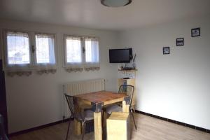 Habitación con mesa, TV y ventanas. en Appartement Le 510 en Aigueblanche