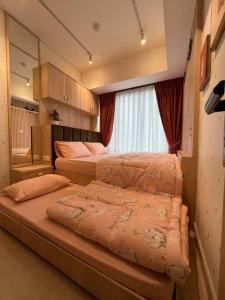 sypialnia z 2 łóżkami i oknem w obiekcie Podomoro City Deli Medan Tower Empire - Japandi Style w mieście Medan