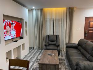 ein Wohnzimmer mit einem Sofa und einem TV in der Unterkunft Meanwood Place Apartments in Lusaka