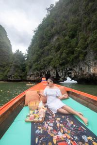 una mujer sentada en un barco con una bandeja de comida en Jamesbond Bungalow Koh Panyee en Ko Panyi