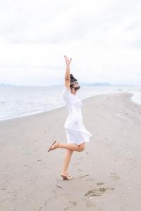 Una mujer con un vestido blanco bailando en la playa en Jamesbond Bungalow Koh Panyee en Ko Panyi