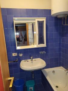 a blue tiled bathroom with a sink and a mirror at Appartamenti Delfina in Pescasseroli
