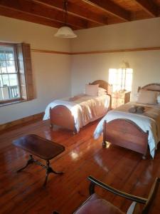 a bedroom with two beds and a chair in it at Bo-Plaas Farmhouse in Bredasdorp