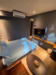 a bedroom with a bed and a tv and a table at 良文旅2館Ryou Hotel Vintage - II in Tainan