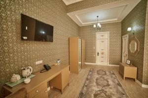 Comfort Hotel Samarkand في سمرقند: غرفة مع تلفزيون على الحائط وغرفة مع مكتب