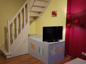 a tv on a dresser in a room with a staircase at Bel appartement duplex avec jardin pour 6 personnes in Luz-Saint-Sauveur