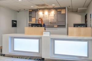 a woman standing behind a counter with two blank monitors at Holiday Inn Express Hotel & Suites Thornburg-S. Fredericksburg by IHG in Thornburg +34 photos