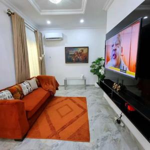 sala de estar con sofá y TV de pantalla plana en Lovely 2 bedroom in osapa london, en Lekki