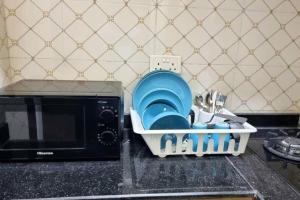un estante de platos con platos y utensilios junto a un microondas en Lovely 2 bedroom in osapa london, en Lekki