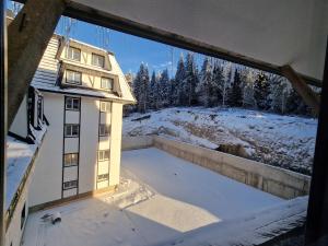 コパオニクにあるXenia Apartmentの雪の中の建物の窓からの眺め