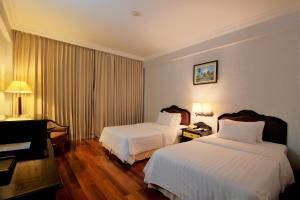 a hotel room with two beds and a desk at Hotel Somadevi Angkor Resort & Spa in Siem Reap