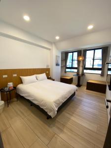 a bedroom with a large bed and two windows at 良文旅 Ryou Hotel Tainan in Tainan