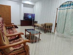 a room with chairs and a table and a television at Kochuparampil House in Idukki