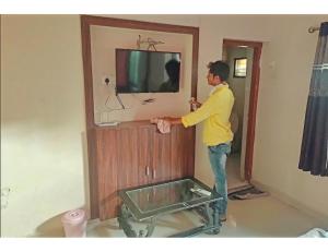 a man standing in a room with a tv at Hotel Anand,Junagadh in Junagadh