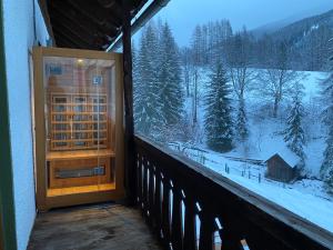 een deur op een balkon met uitzicht op een met sneeuw bedekt bos bij Nockalm Cottage in Bad Kleinkirchheim