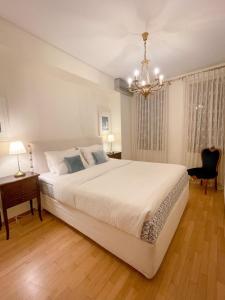 ein Schlafzimmer mit einem großen weißen Bett und einem Kronleuchter in der Unterkunft Villa Voulgari in Ioannina