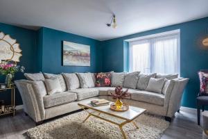 uma sala de estar com um sofá grande e paredes azuis em Wisteria View with hottub & cabin sleeps 20 em Chippenham