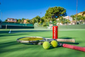 rakieta tenisowa i dwie piłki tenisowe na korcie tenisowym w obiekcie Ideal Property Mallorca - Sol de Mallorca 2 w Cala Mesquida