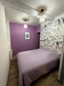 Un dormitorio con una pared púrpura y una cama en T2 Centre ville La Licorne 2, en Pont-Audemer