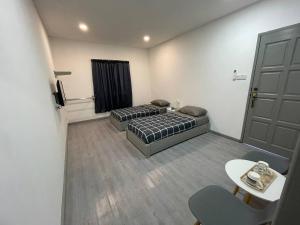 een kamer met 2 bedden en een tafel en een deur bij Alor Lanchang Roomstay in Arau