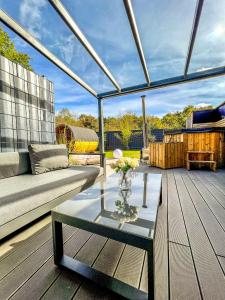 eine Terrasse mit einem Sofa und einem Glastisch in der Unterkunft JUNIPRO Luxury Apartments in Nohfelden