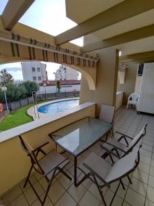 eine Terrasse mit einem Tisch und Stühlen sowie einem Pool in der Unterkunft Flamingo Sol Home in Torremolinos